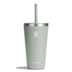 a green tumbler cup with a straw sticking out of it's side, on a white background