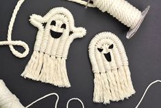 two white knitted ghost decorations next to a spool of thread and twine