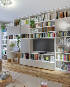 a living room filled with lots of white furniture and bookshelves full of books