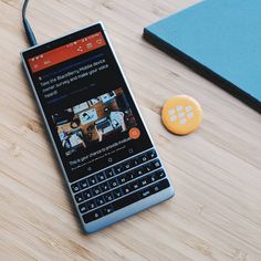 a cell phone sitting on top of a wooden table next to a keyboard and mouse