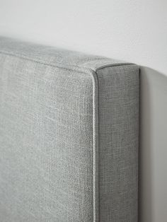 a close up view of the back of a gray couch with white walls in the background