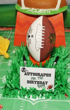 a football sitting on top of a green field next to a sign that says autographs for the birthday boy