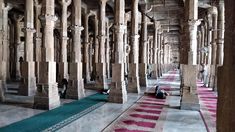 the interior of an old building with columns and rugs