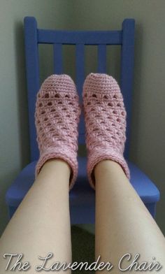 the legs of a woman wearing pink crocheted slippers sitting on a blue chair