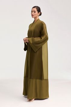 Elevate your wardrobe with the Estee Viscose Open Abaya in Olive Night. Crafted from luxurious viscose, this stunning abaya features elegant flare sleeves and a unique sheer design with solid viscose trim. Breathable and luxurious, this abaya will be your new go-to for sophisticated and exclusive style. Model is 5'7" and is wearing size XS/58". Inner Abaya Dress, Organza Abaya Design, Wedding Abaya Design, Unique Abaya Designs, Transparent Wardrobe, Traditional Abaya, Luxurious Abaya, Open Abaya Style, Formal Abaya