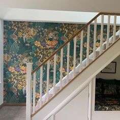 a stair case next to a floral wallpaper