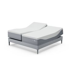 two mattresses sitting next to each other on a white surface, one is folded up and the other has no sheets