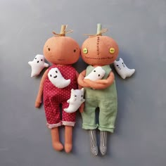 two dolls are laying next to each other on a gray surface, one is holding a cat