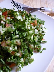 a white plate topped with lettuce and tomato salad next to a silver fork