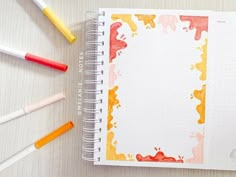 an open notebook with paint splattered on it and colored pencils next to it