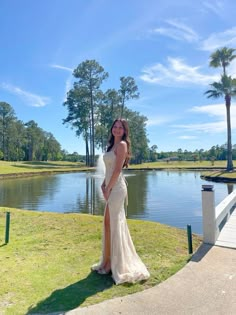 a woman in a long dress standing by the water