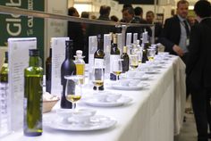 a long table with wine bottles and glasses on it, along with people in the background