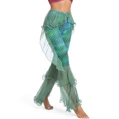 a woman in a red top and green mermaid costume is dancing with her hands behind her head