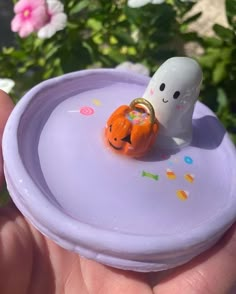 a hand holding a small halloween decoration on top of a purple plate with sprinkles