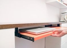 a person holding a laptop on top of a shelf