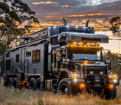 a large truck parked in the middle of a field with trees and grass behind it