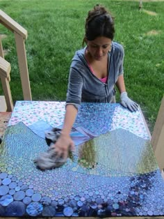 a woman is working on a mosaic table