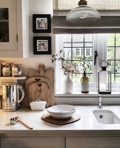 a kitchen counter with plates and bowls on it next to a window in the background