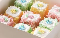 a box filled with colorfully decorated cupcakes on top of a wooden table