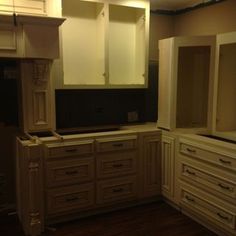 an empty kitchen with white cabinets and wood flooring in the middle of the room