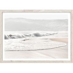 an ocean scene with waves coming in from the shore and mountains in the distance, framed in white wood