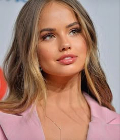 a close up of a woman wearing a pink suit and diamond necklace on her neck