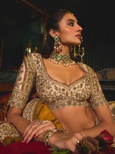 Step into refined elegance with this opulent gold lehenga, a stunning embodiment of artistry and tradition. Crafted from rich raw silk, the lehenga features intricate filigree work that gracefully dances across the fabric like golden vines. Hand-embroidered with vintage gold zari and shimmering sequins, the blouse and lehenga skirt showcase a beautiful romance depicted through floral and bird motifs. Paired with a striking maroon dupatta adorned with a delicate kiran border, this ensemble captures the essence of timeless beauty, making it perfect for any grand occasion. Maroon Dupatta, Raw Silk Embroidery, Gold Lehenga, Lehenga Skirt, Gold Blouse, Bird Motif, Gold Fabric, Lace Border, Sequins Embroidery