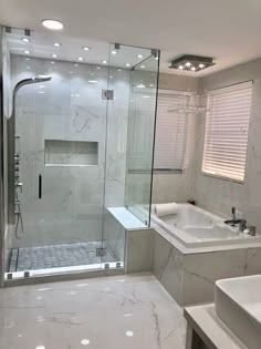 a bathroom with a walk in shower next to a white sink and bathtub under lights