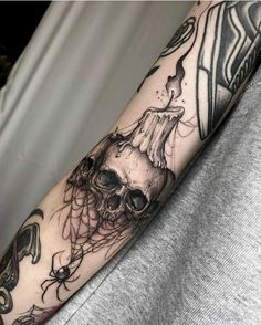 a man's arm with a skull and spider web tattoo on it