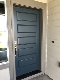 a blue front door is open on a white house with gray trim and sidelights