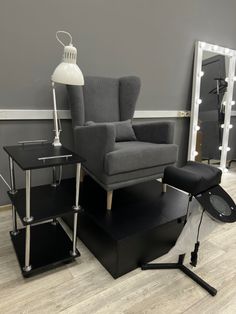 a chair and table in front of a mirror on the floor with lights around it