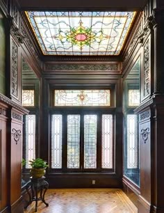 an empty room with stained glass windows and wooden flooring on the walls, along with a bench