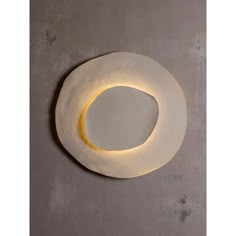 a white plate with a yellow circle on it's side, against a gray wall