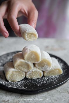 a person is scooping sugar into some pastries on a black and white plate