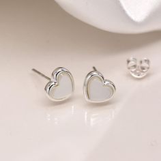 A stunning pair of sterling silver mother-of-pearl heart stud earrings that can be personalised with an optional message on a separate card Not to be found anywhere on the high street, our beautiful heart studs are crafted from the finest sterling silver. Featuring gorgeous natural mother of pearl gemstones set in a beautiful silver heart shaped setting, these dainty silver heart stud earrings feature a classic butterfly and post fastening and are suitable for almost any age. Make your earrings Elegant Silver Heart Earrings For Mother's Day, White Dainty Earrings With Heart Charm, White Dainty Heart Earrings For Pierced Ears, Dainty White Heart Earrings For Pierced Ears, White Heart Charm Earrings, Classic Heart-shaped White Jewelry, White Sterling Silver Earrings As A Gift For Her, Classic Heart Shaped White Jewelry, Elegant White Pierced Heart Earrings