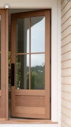 two wooden doors are open on the side of a house in front of a window