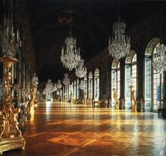 an ornate hall with chandeliers and mirrors on the walls is lit by lights