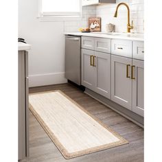 a kitchen with white cabinets and gold handles