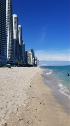 a sandy beach with tall buildings in the background