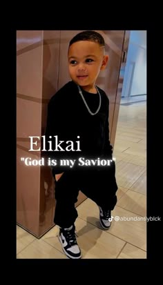 a young boy is standing in front of a wall with the words eliai god is my savor