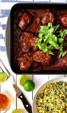 the meal is ready to be eaten and served on the table with limes, cilantro, corn, and rice