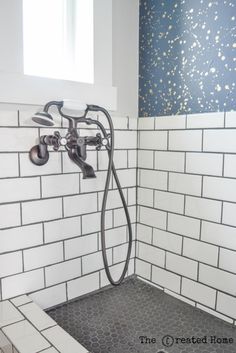 a bathroom with white and blue tile walls, shower head and hand held faucet