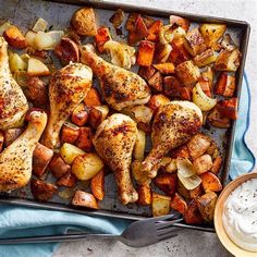 chicken and potatoes on a baking sheet with a bowl of ranch dressing next to it