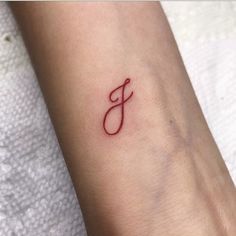 a small tattoo with the letter j on it's wrist, in red ink