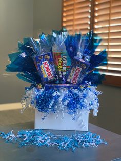 a box filled with candy and blue streamers sitting on top of a table next to a window