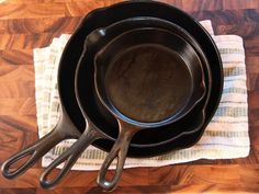 three cast iron skillets sitting on top of a kitchen towel