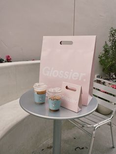 two cups of coffee sitting on top of a table next to a pink paper bag