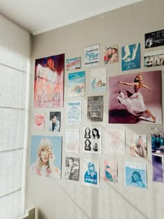 a wall covered in posters and pictures next to a window