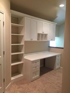 an empty room with white cupboards and drawers on the wall, carpeted floor