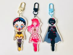 three keychains with cartoon characters on them sitting next to each other in front of a white background